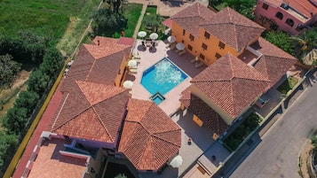 Vista aérea de uma propriedade com vários edifícios, piscina e áreas de estar ao ar livre.