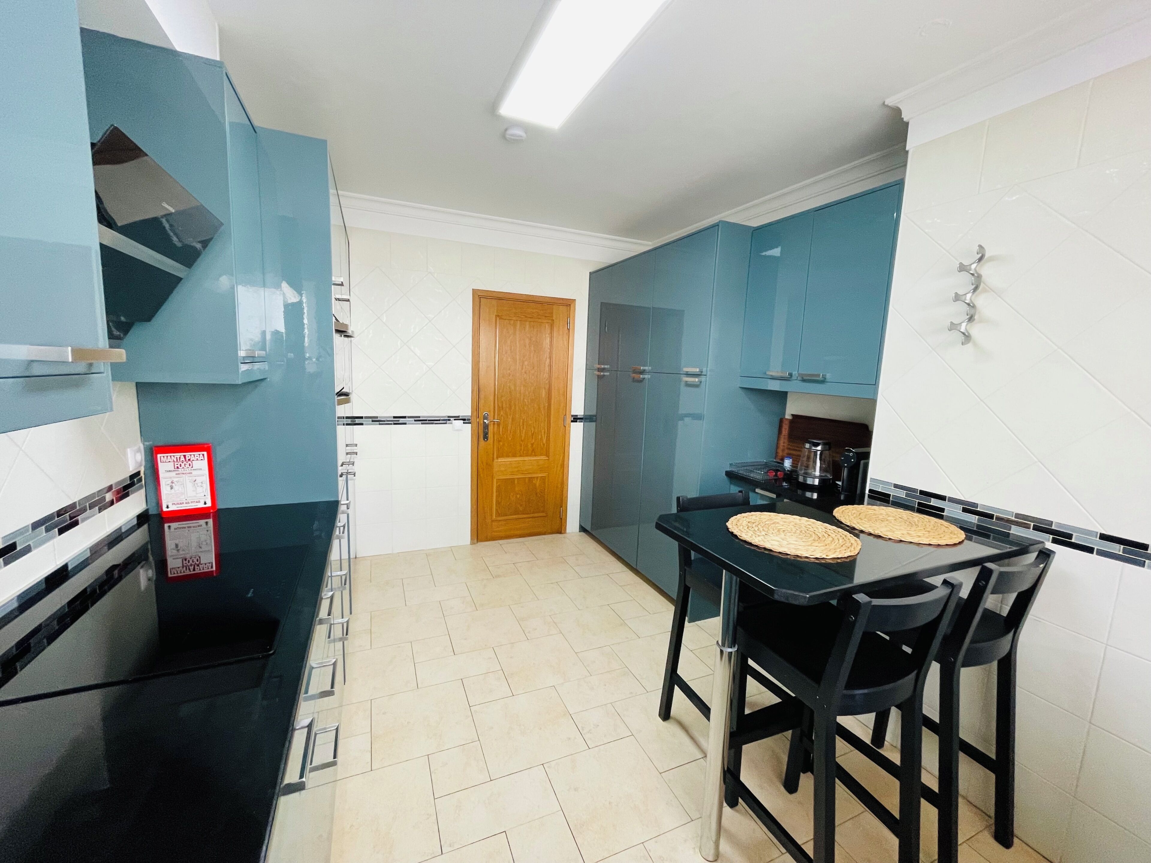 A compact kitchen with a black countertop, a wooden door, and blue cabinets.