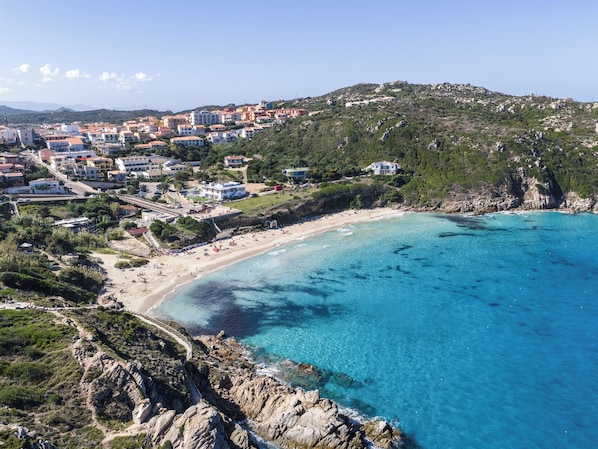 A coastal town with a beach, rocky cliffs, and residential buildings. - Cozy 3 Guest Apartment With Pool (Santa Teresa di Gallura)