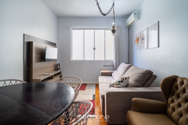 A modern living room with a sofa, a dining table, and a TV. - 2 Bedroom Apartment in Downtown Floripa Ebe0804 (Florianópolis)