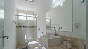 A modern bathroom with a glass-enclosed shower, a large sink, and a mirror. - 2 Bedroom Apartment in Downtown Floripa Ebe0804 (Florianópolis)