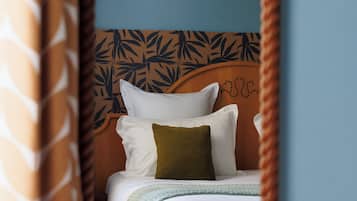 A bedroom with a bed, pillows, a headboard with a leaf pattern, and a mirror reflecting the room.