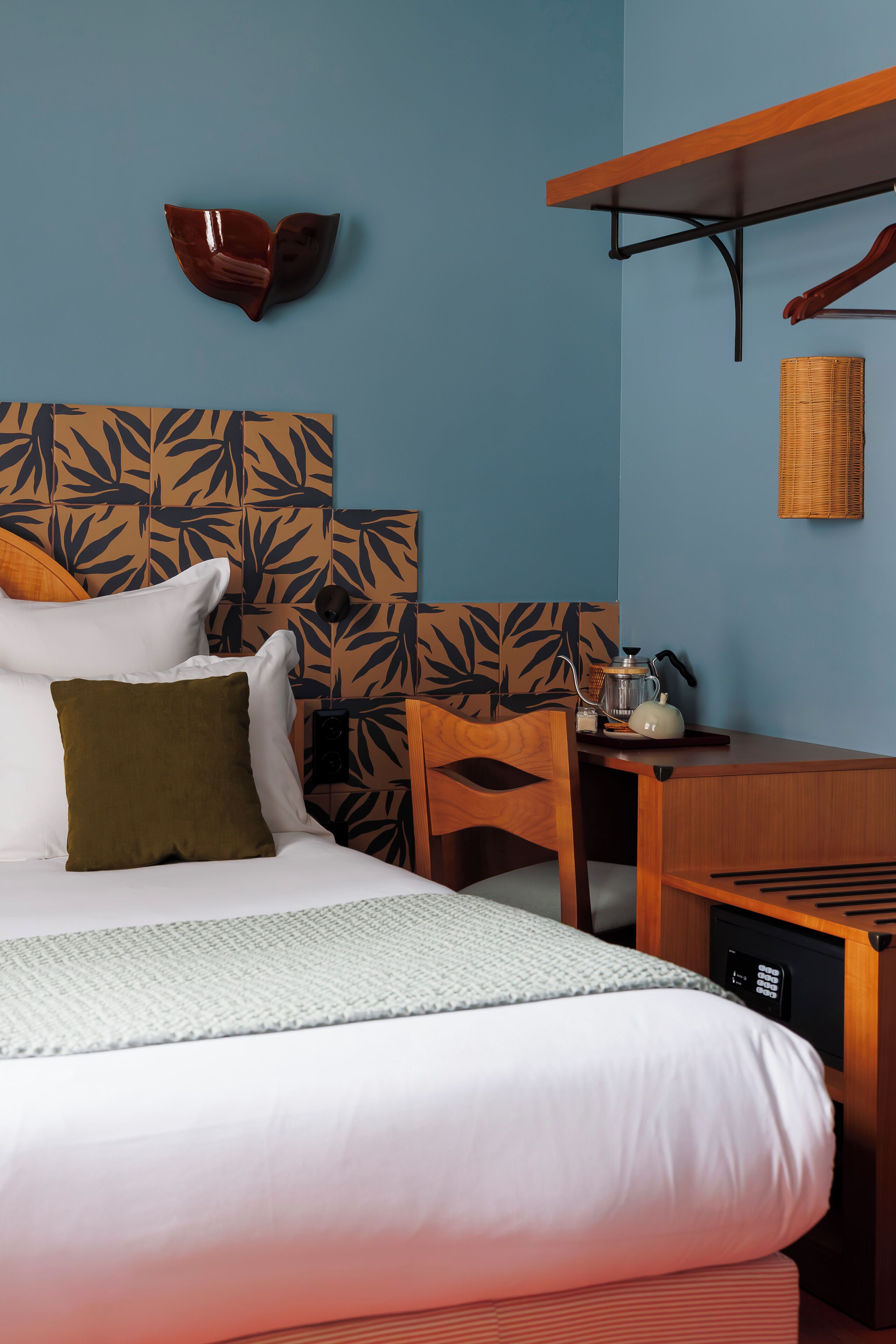 A neatly arranged hotel room with a bed, a desk, and a chair.