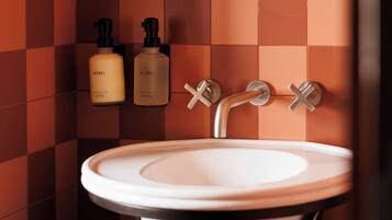 A bathroom with a white sink, two soap dispensers, a towel, and a woven basket.