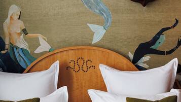 A room with two beds, a wooden headboard, and a mural of mermaids on the wall.