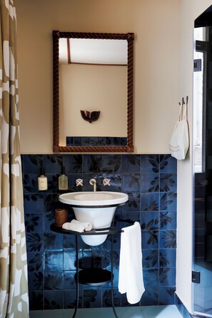 A bathroom with a white sink, a mirror above it, and blue patterned tiles. - Babel Lille (Lille)