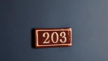 Pared azul escura com uma placa de latão retangular exibindo o número 203.