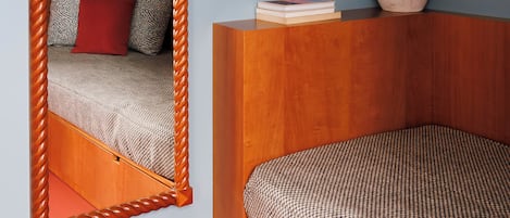 A bedroom with a wooden headboard, a large mirror, a bedside table with a vase, and a patterned bedspread.