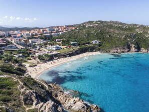 A coastal town with a beach, rocky cliffs, and residential buildings. - Comfy 4 Guest Apartment With Pool (Santa Teresa di Gallura)
