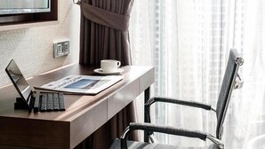 Une chambre d’hôtel avec un bureau en bois, un ordinateur portable, une tasse et une chaise.