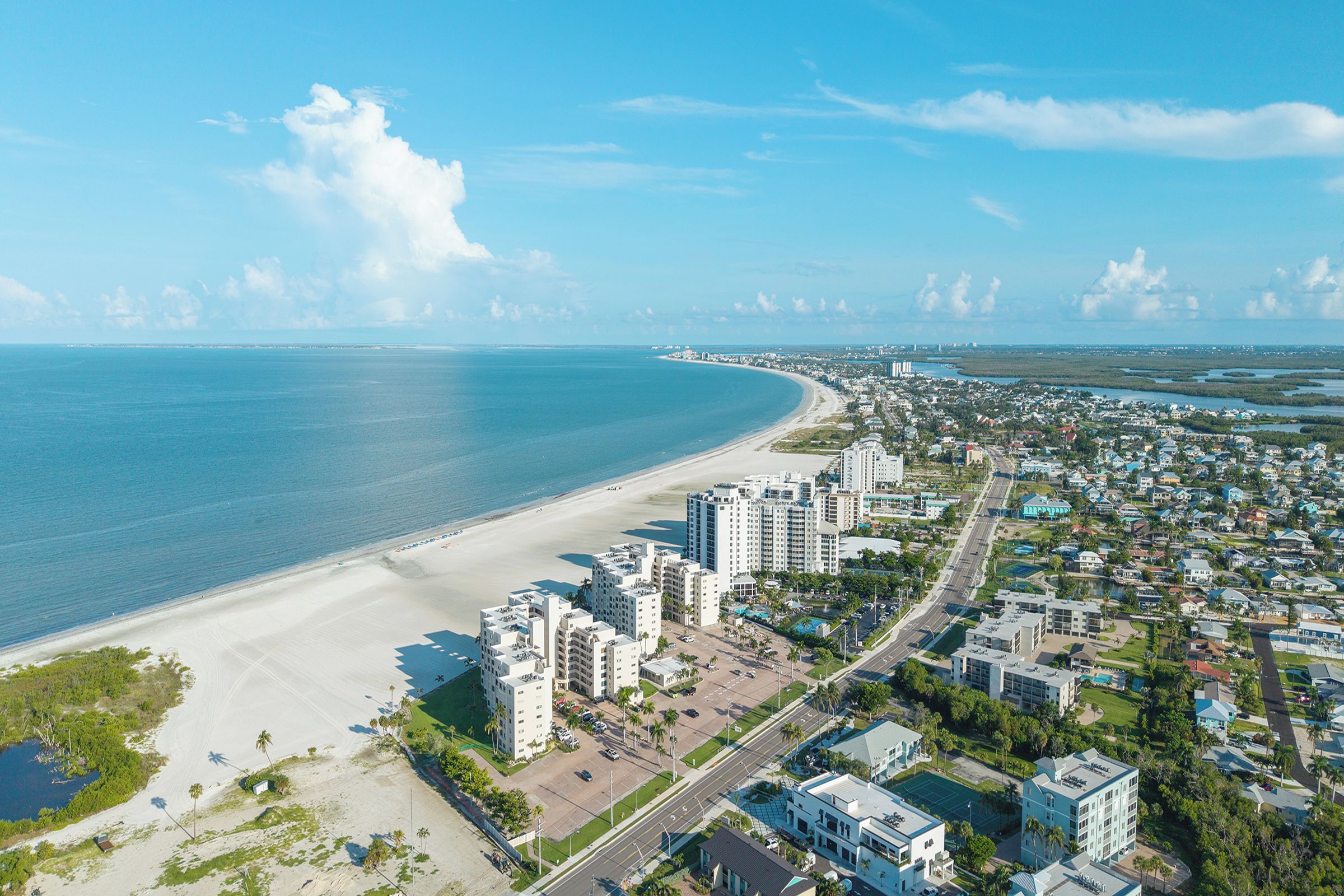 Un paisaje urbano costero con una playa, edificios altos y cielo despejado.