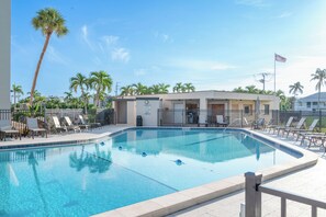 Piscina com espreguiçadeiras e palmeiras.