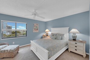A bedroom with a bed, a nightstand, a lamp, a chair, a ceiling fan, and a window with blinds. - SANDARAC 604b BEACHFRONT 2B/2B VACATION CONDO w/  GULF VIEW, RESORT POOL! (Fort Myers Beach)