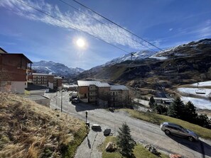 Uma vila montanhosa com edifícios, área de estacionamento e um teleférico de esqui.