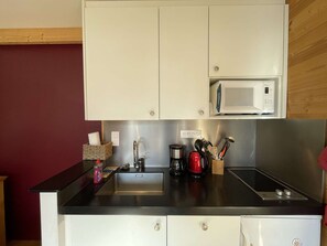 A compact kitchen with a microwave, sink, and stainless steel appliances. - Beautiful cozy apartment near slopes in Les Menuires with parking (Les Menuires)