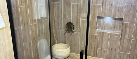 Ein modernes Badezimmer mit einer begehbaren Glasdusche, einem Holzbadschränken und einem großen Waschbecken.