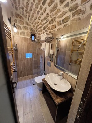 Une salle de bain moderne avec un plafond en pierre, un meuble-lavabo en bois, un grand miroir et un espace douche.
