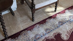 Ein Zimmer mit Steinwänden, einem Bett, einem Heizgerät und einem gemusterten Teppich.