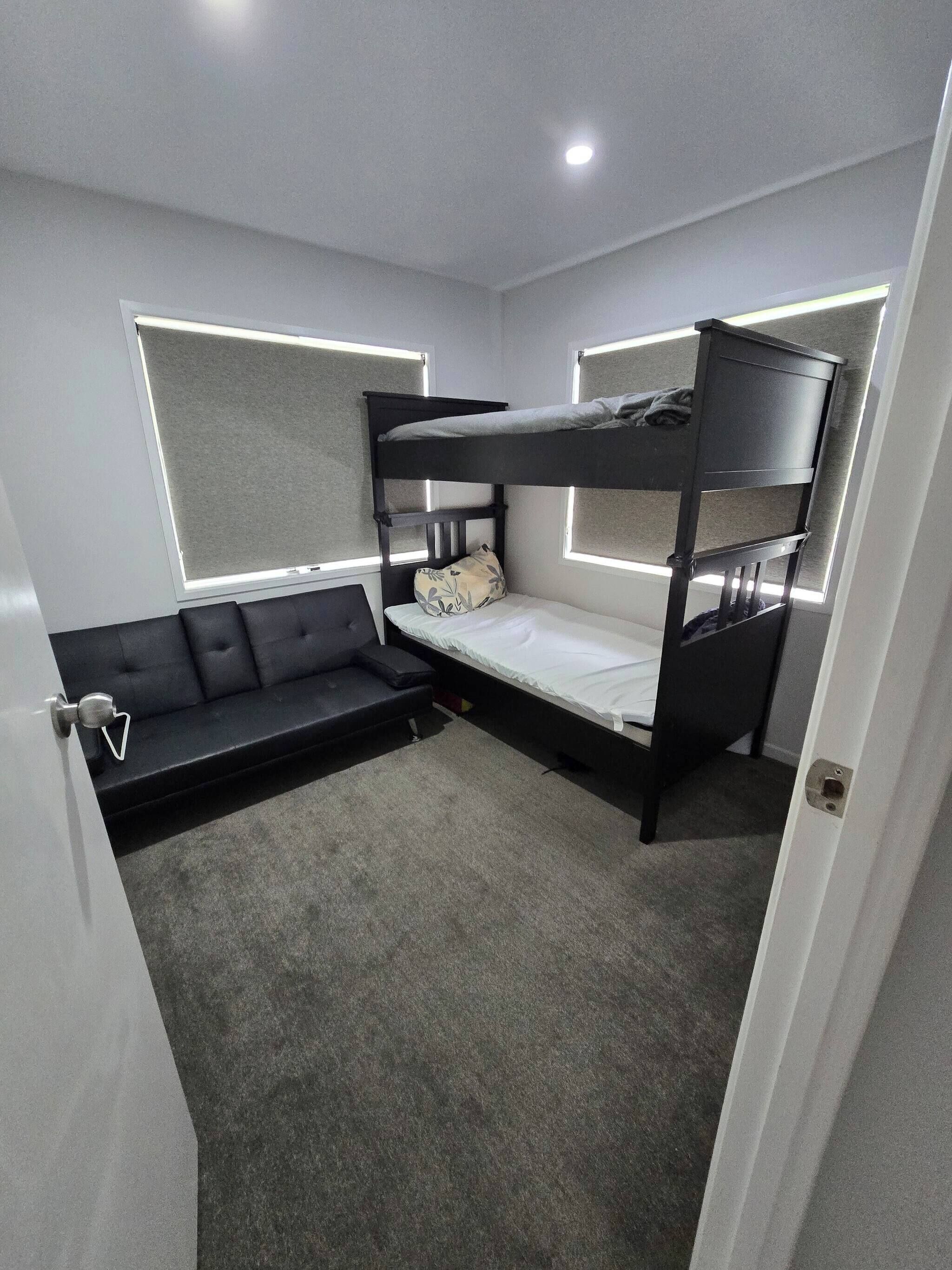 A compact room with a bunk bed, a sofa, and a small table.