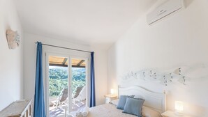 A bedroom with a bed, a nightstand, a dresser, and a view of a balcony with chairs. - Complex With Pool and sea View (Arzachena)