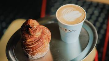 A croissant and a cup of coffee on a tray.