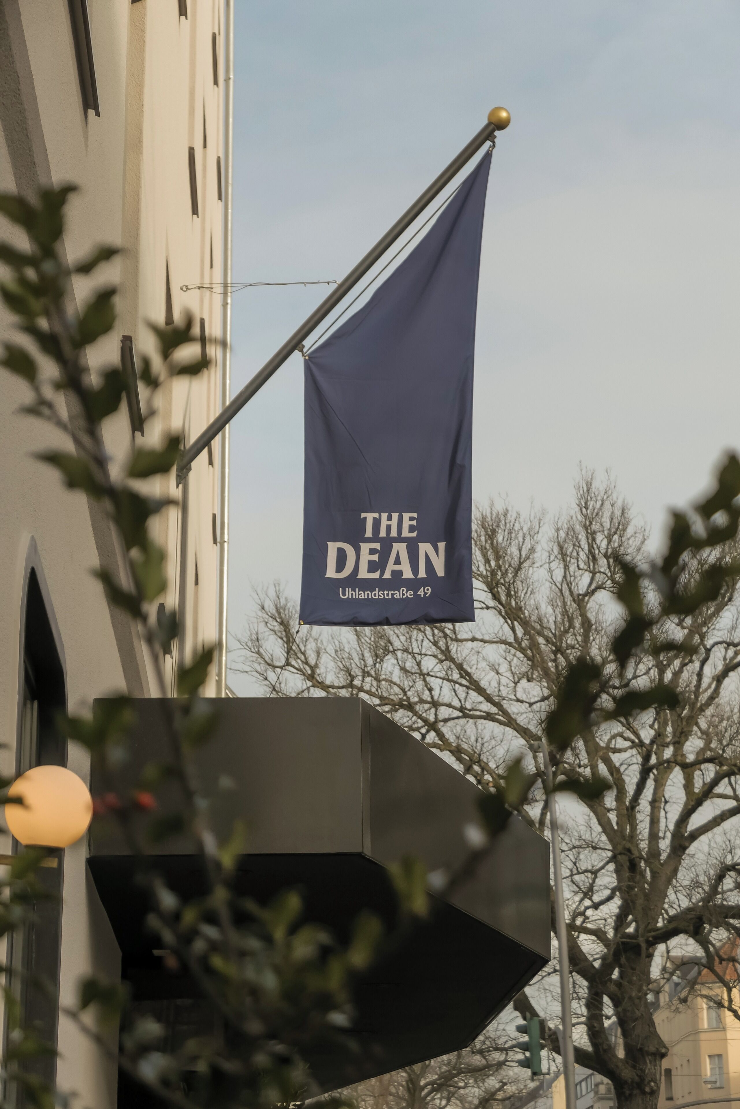 A flag with "THE DEAN" and "Uhlanstrasse 49" on a building.
