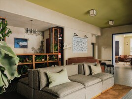 Ein Wohnzimmer mit einer Couch, einem Holzschrank mit Pflanzen, einem Wandbild und einem Hinweisschild.