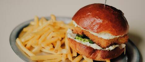 Un hamburger accompagné d’une portion de frites, le tout servi sur une assiette en métal.