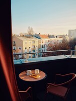 Ein Balkon mit Tisch und zwei Stühlen mit Blick auf eine Häuserreihe.