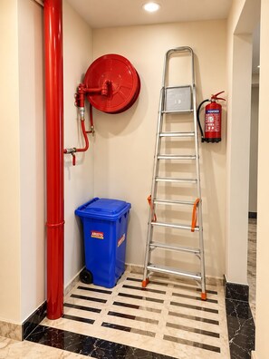 A corner with a red fire hose, a blue trash bin, and a metal ladder. - Hotel Vindhya Ganga Inn (Varanasi)