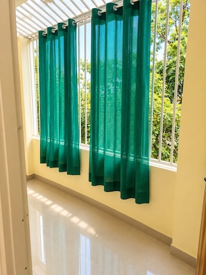 A room with a large window, green curtains, and a tiled floor. - Hotel Vindhya Ganga Inn (Varanasi)