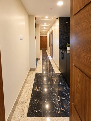 A hallway with a marble floor, wooden cabinets, and a door on the right. - Hotel Vindhya Ganga Inn (Varanasi)