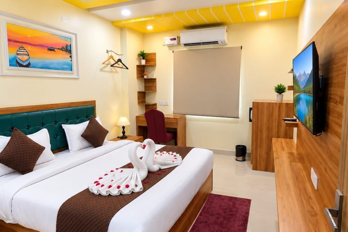 A hotel room with a bed, a desk, a TV, and a ceiling fan.
