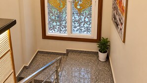 Eine Treppe mit Metallgeländer führt zu einer Zwischenebene mit einer dekorativen Glashütte, verziert mit Pfauenmotiven.