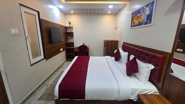 Ein Hotelzimmer mit einem großen Bett, einem Fernseher, einem Schreibtisch und einem Kleiderschrank.