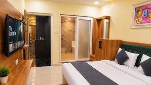 Ein Hotelzimmer mit Bett, Schreibtisch, Fernseher, Badezimmer und Deckenventilator.