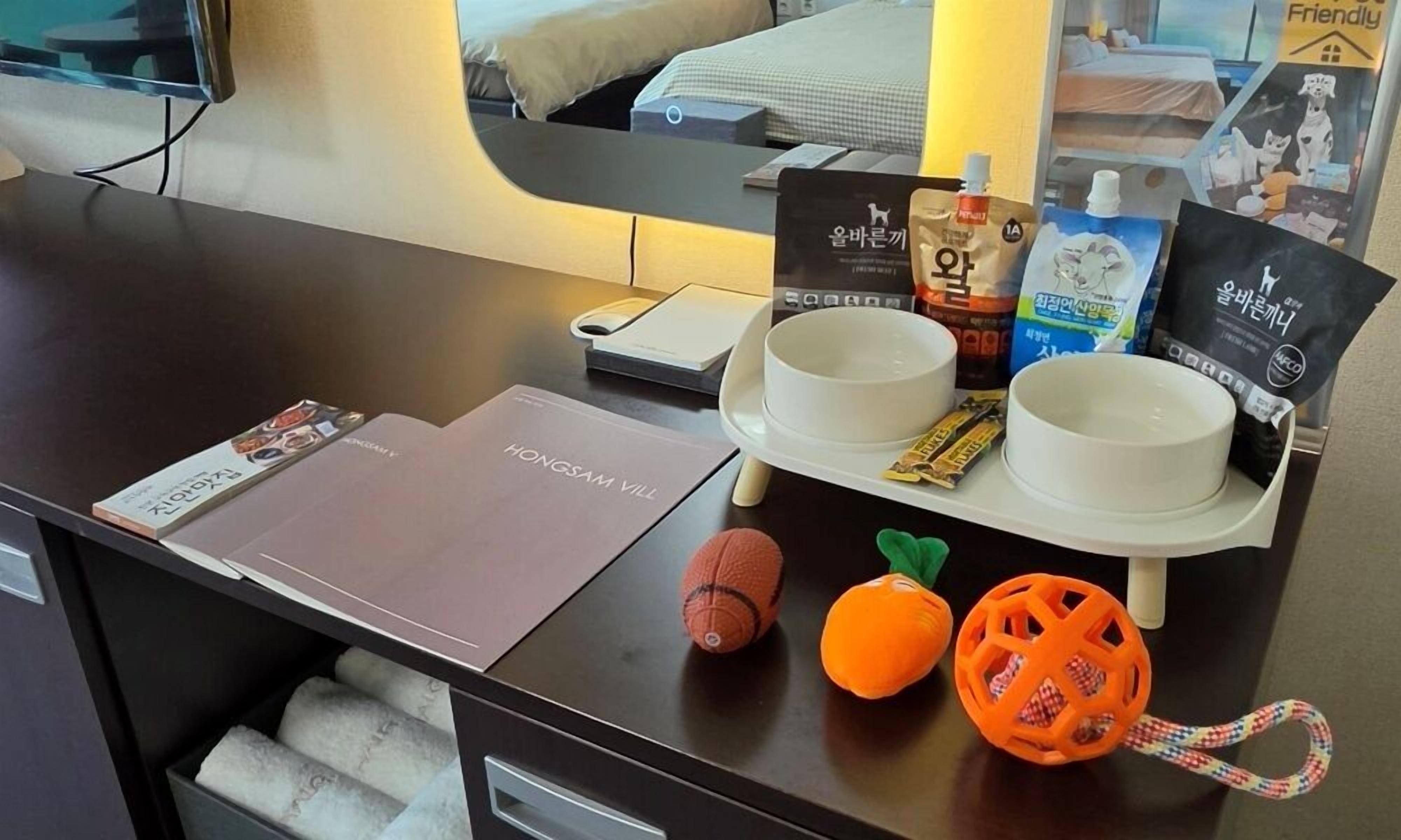 Un comptoir d’accueil d’hôtel avec un lit en arrière-plan, une balance, un bol, un jouet pour chat et un jouet pour chien.