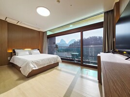 Una habitación de hotel moderna con una cama grande, un escritorio y un balcón con vistas a la montaña.