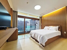 Una habitación de hotel moderna con una cama grande, un escritorio y un balcón con vistas a la ciudad.