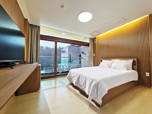 A modern hotel room with a large bed, a desk, and a balcony with a view of the city. - Jinan redginseng Ville (Jinan)
