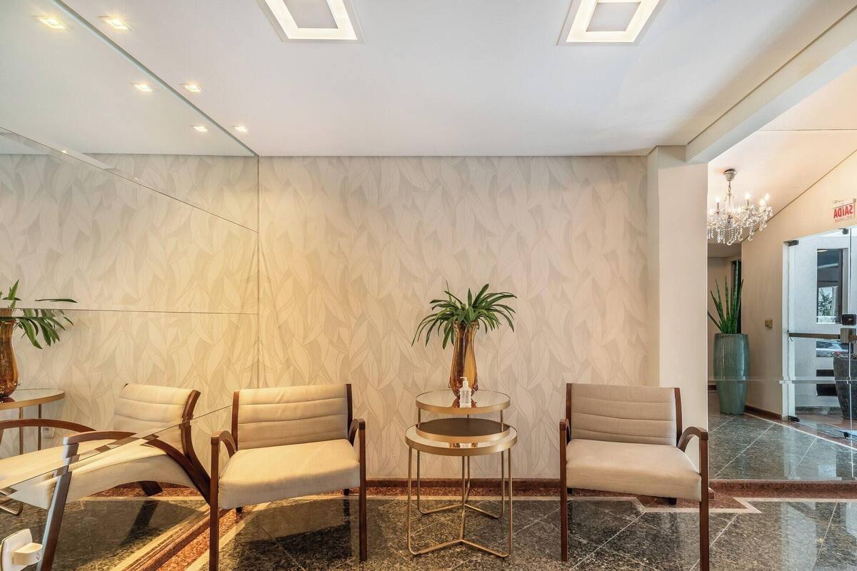 A lobby with a marble floor, two sofas, a round table, and a potted plant.