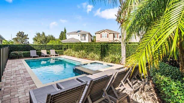 En swimmingpool med liggestole, jacuzzi og en fliseterrasse.