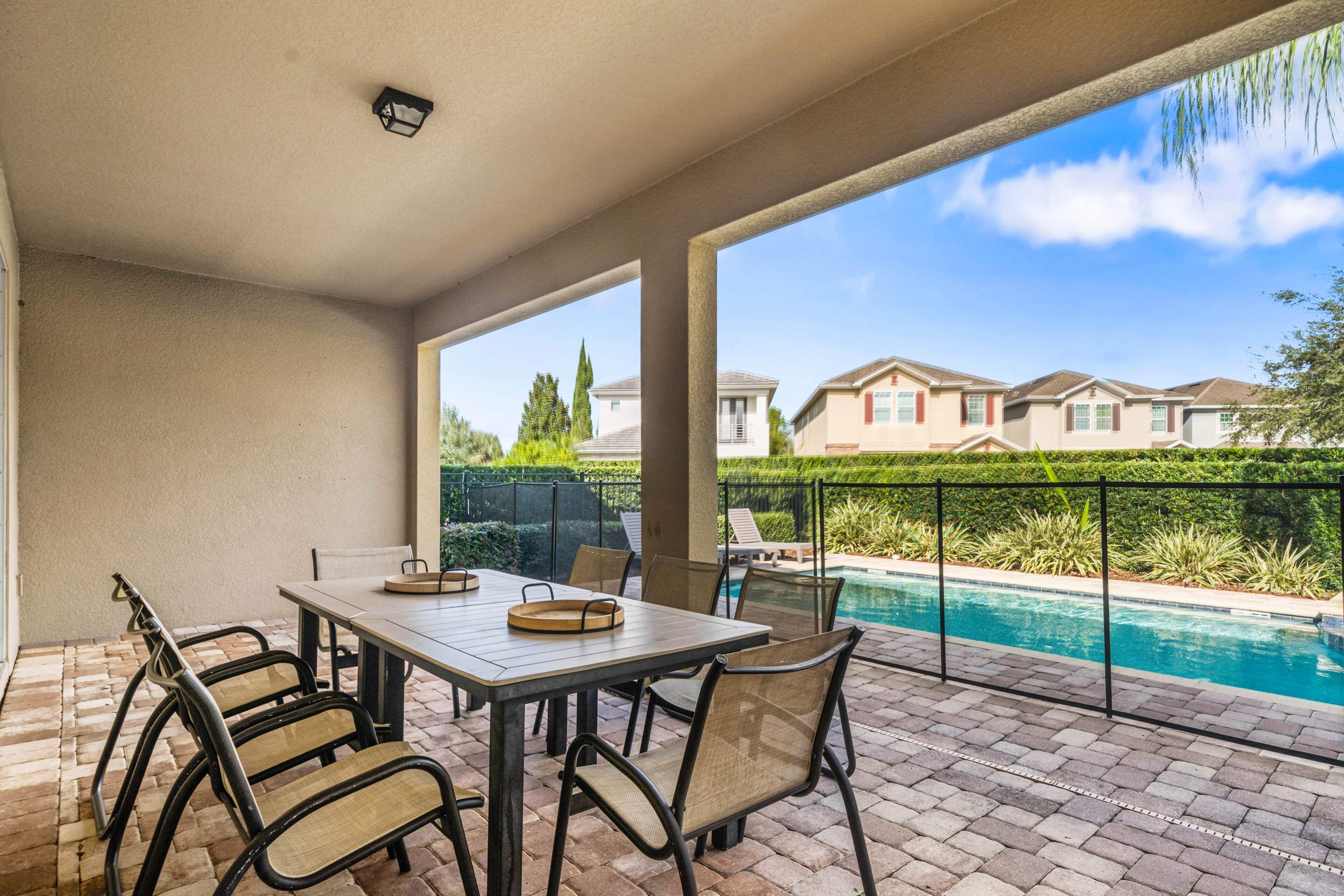 Eine Außenpatio mit Pool, Tisch und Stühlen sowie Blick auf benachbarte Häuser.