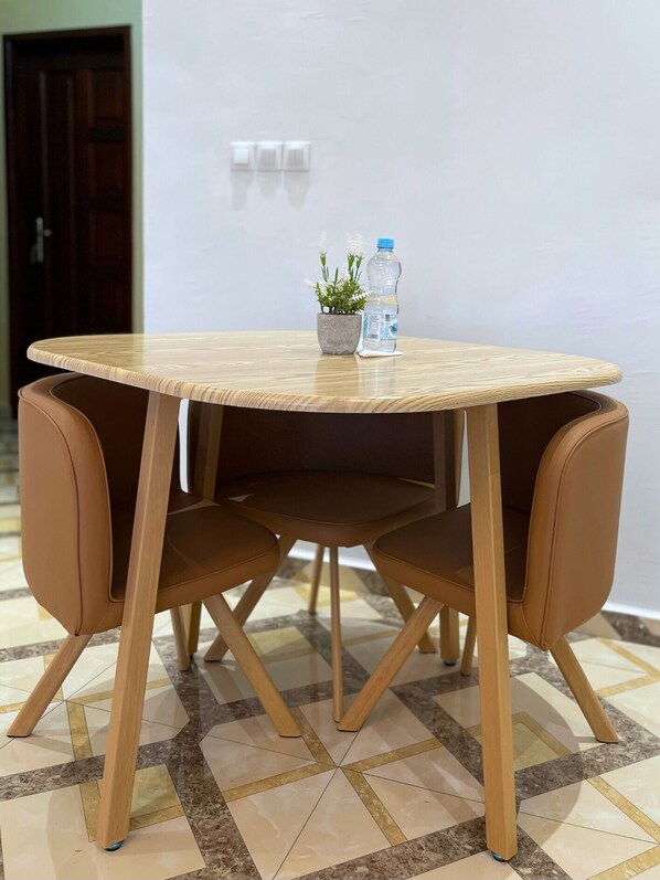 Ein runder Holztisch mit einem Blumentopf und zwei Wasserflaschen darauf.