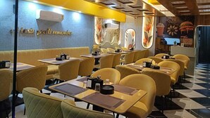 A restaurant interior with yellow booths, a checkered floor, and a wall with a floral design. - Hotel Akshay (Jaipur)