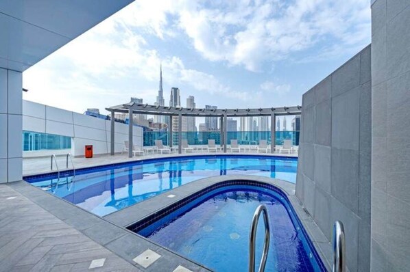 An indoor swimming pool with a view of the city skyline, including a prominent skyscraper. - Stayshort - Stunning 1 Bedroom Sleeps 4 in Business Bay (Dubai)