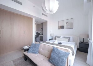 Ein modernes Hotelzimmer mit einem großen Bett, einer Sitzecke, einem Schreibtisch und einem Kleiderschrank.