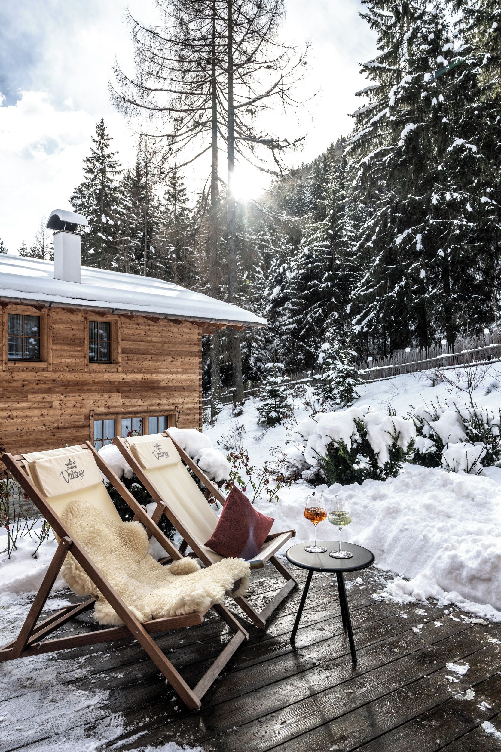 Eine Holzhütte mit zwei Lounge-Sesseln und einem kleinen Tisch mit Gläsern.
