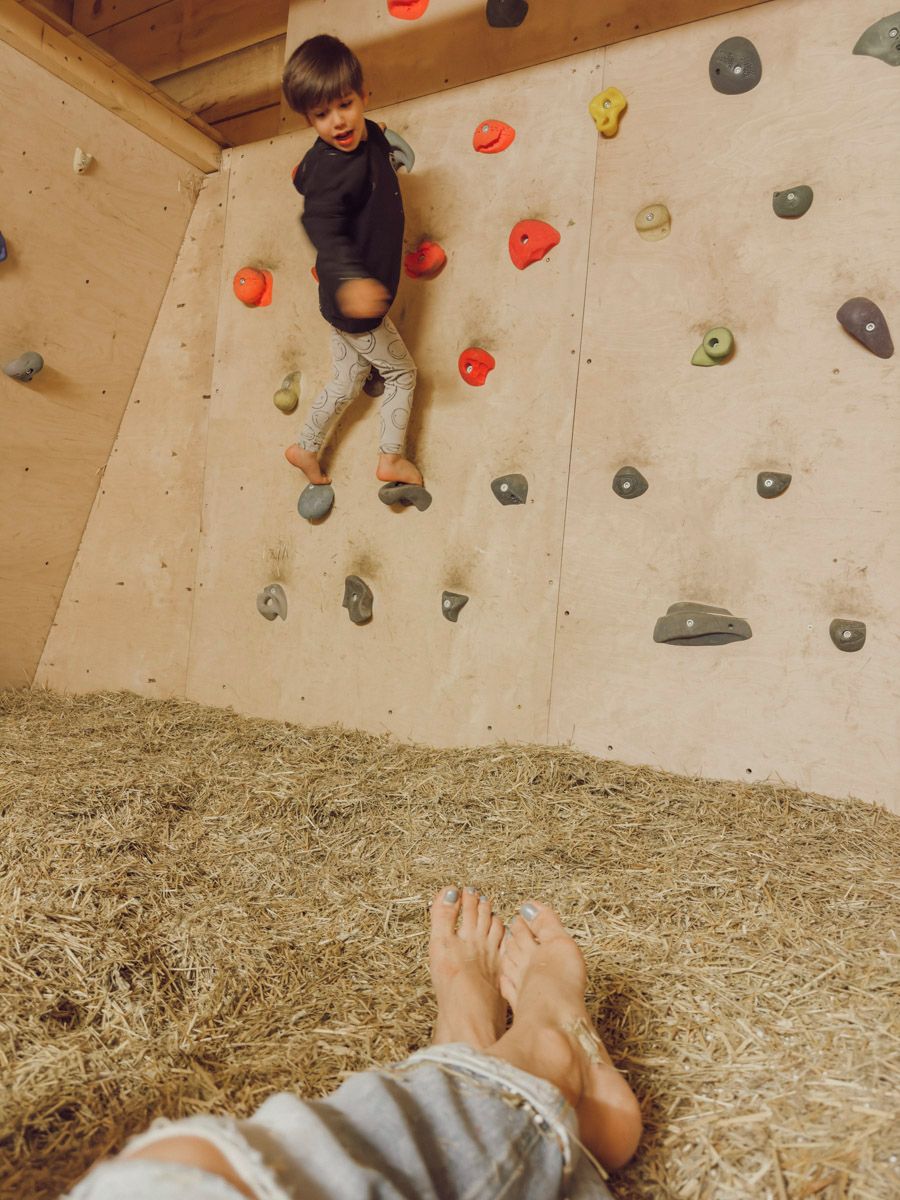 Un bambino arrampica su una parete di legno con appigli di diversi colori.