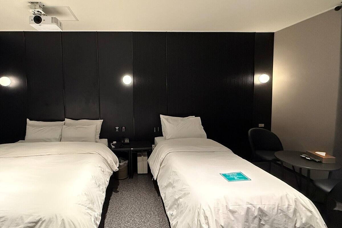 Una habitación de hotel con dos camas, un escritorio, una silla y una mesita.